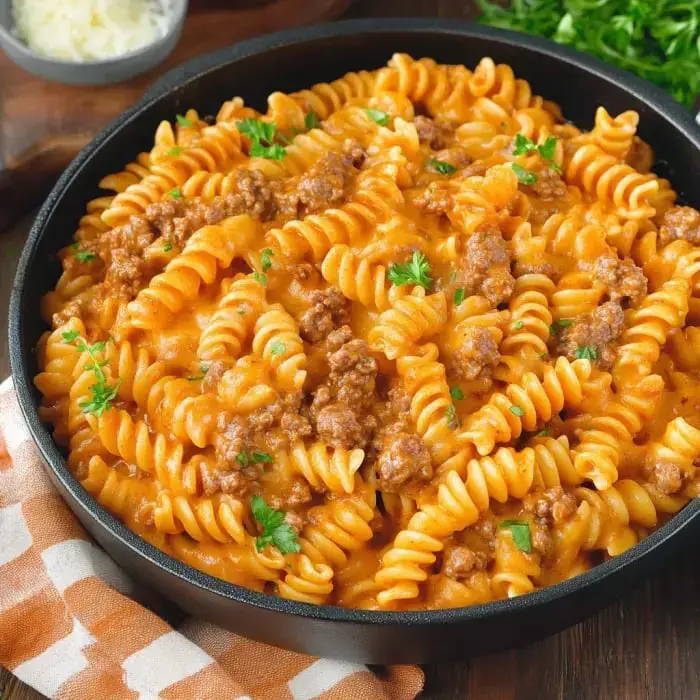 A bowl of curly pasta with creamy sauce and beef, sprinkled with parsley on top.