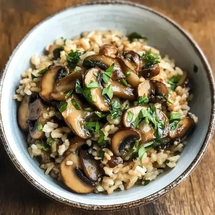 A bowl loaded with brown rice, golden mushrooms, and chopped parsley on top.