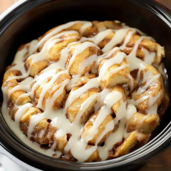 Zoomed-in bowl of cinnamon roll bites covered with sweet cream cheese icing.