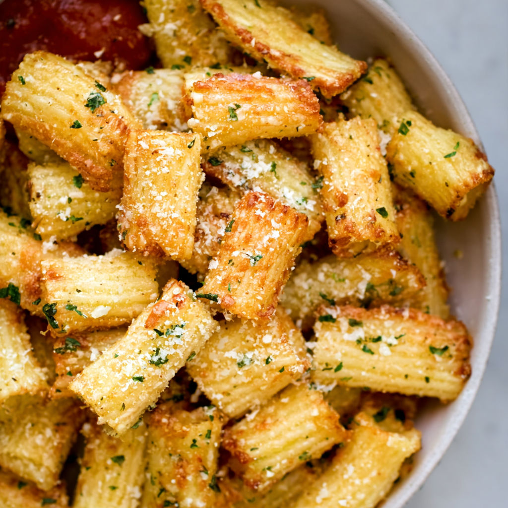 A bowl of pasta chips with cheese and seasoning.