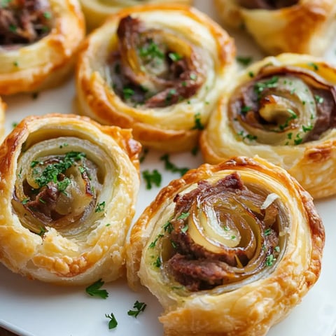 A plate of golden spiral pastries stuffed with beef and onions, topped with fresh parsley.