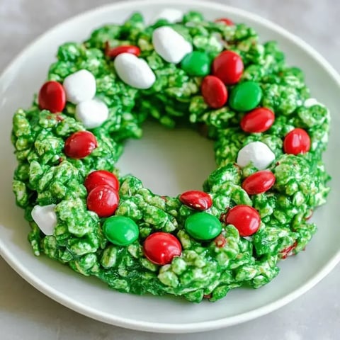 Round, green cornflake wreaths with red and green candy tucked in, white marshmallow dots, all arranged on a plate.