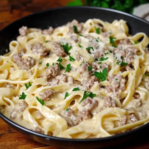 A bowl piled with creamy noodles, ground beef, and sprinkles of parsley.