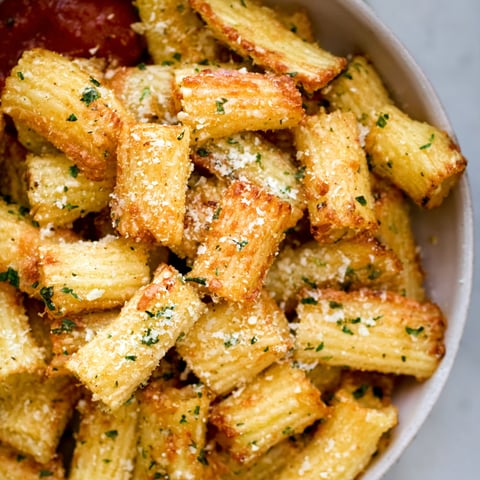 A bowl of pasta chips with cheese and seasoning.