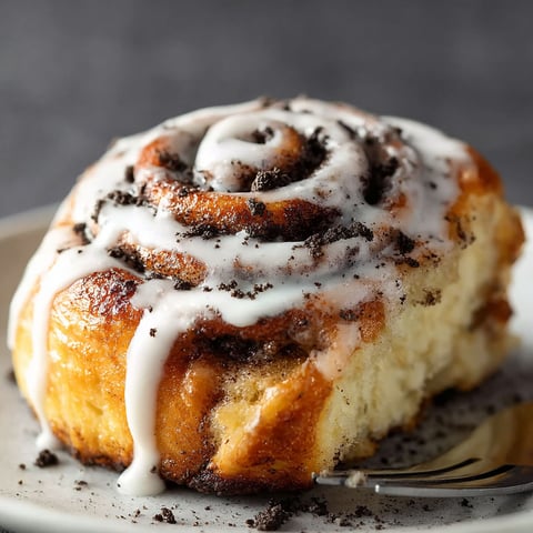 A cinnamon roll with white icing and chocolate chips.