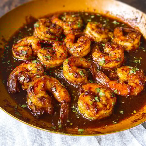 A plate of shrimp in a brown sauce.