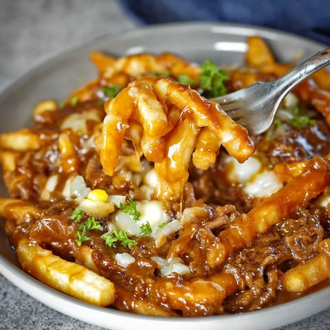 A fork is being used to eat a plate of food.